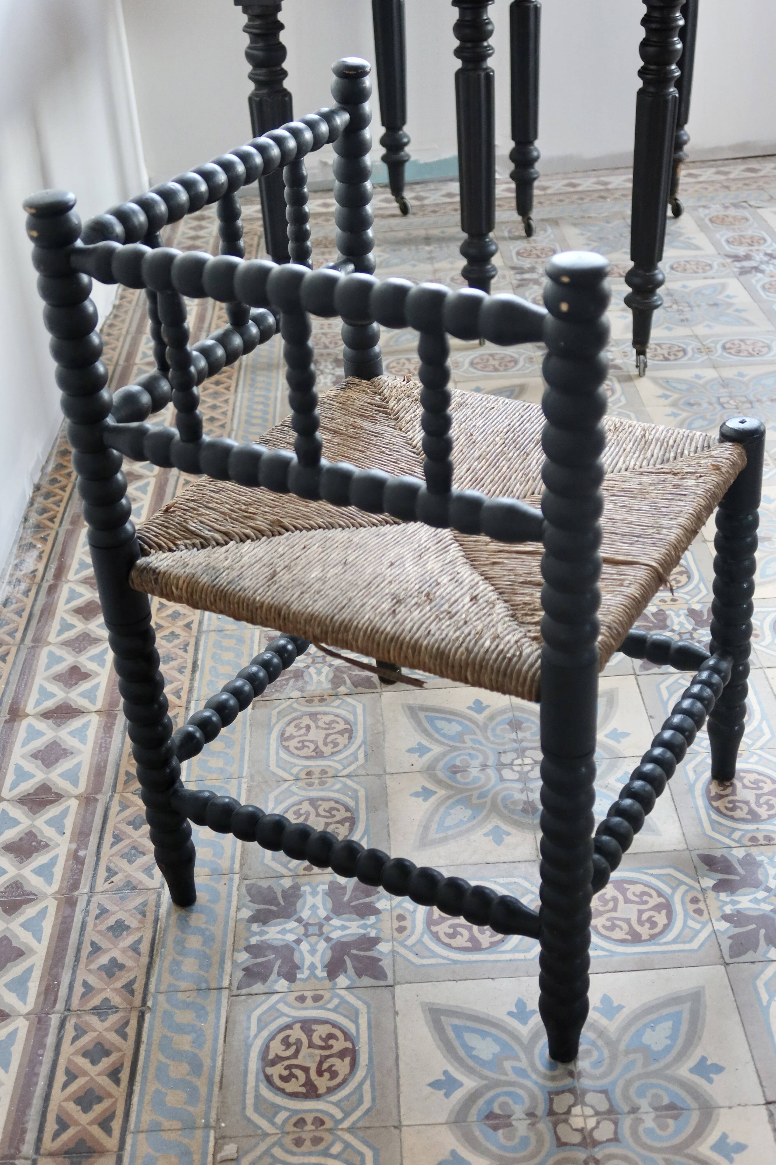 Antique black turned wood corner chair with a straw seat.