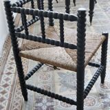 Antique black turned wood corner chair with a straw seat.