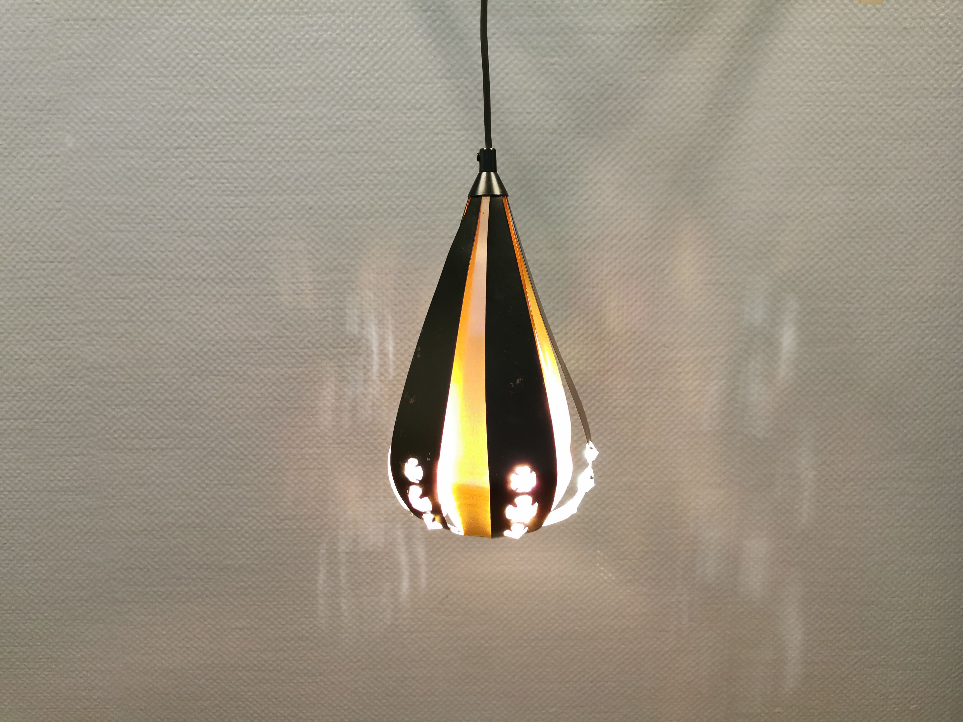 Hanging lamp in thin metal pieces, copper colored and black with prisms.