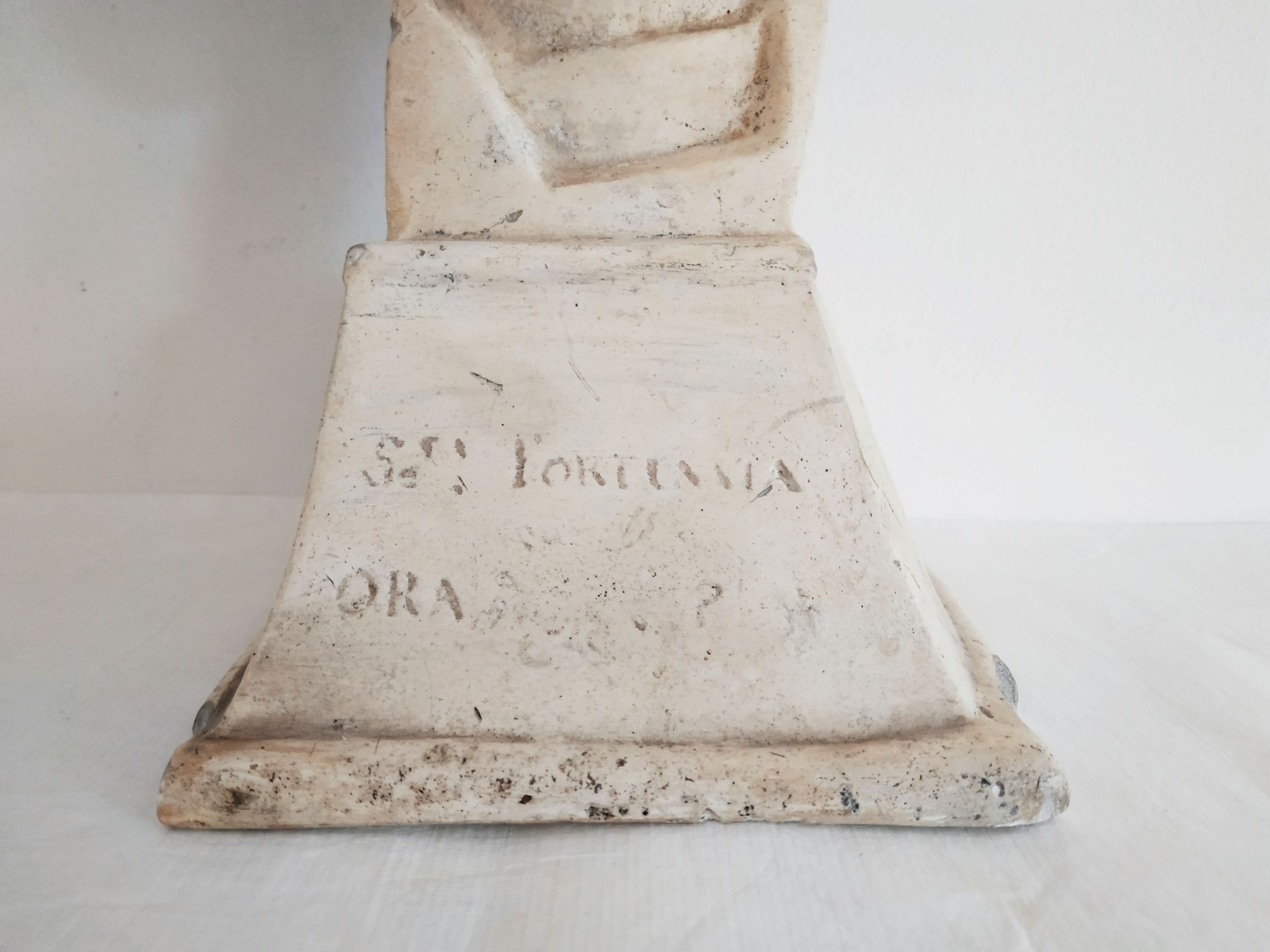 Bust of woman in plaster on pedestal with inscription