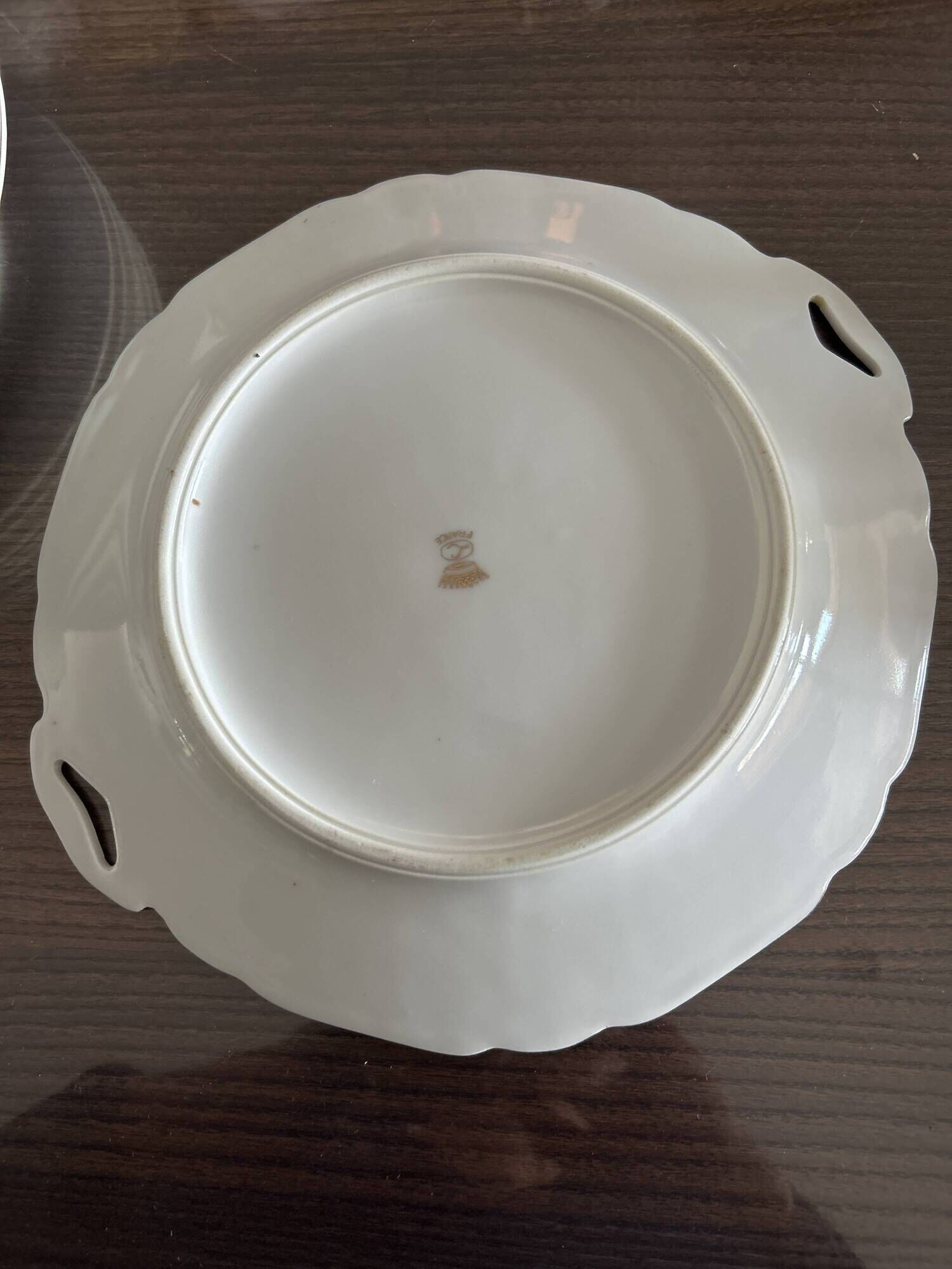 This dish appears to be a serving dish or a round plate with handles made of porcelain.