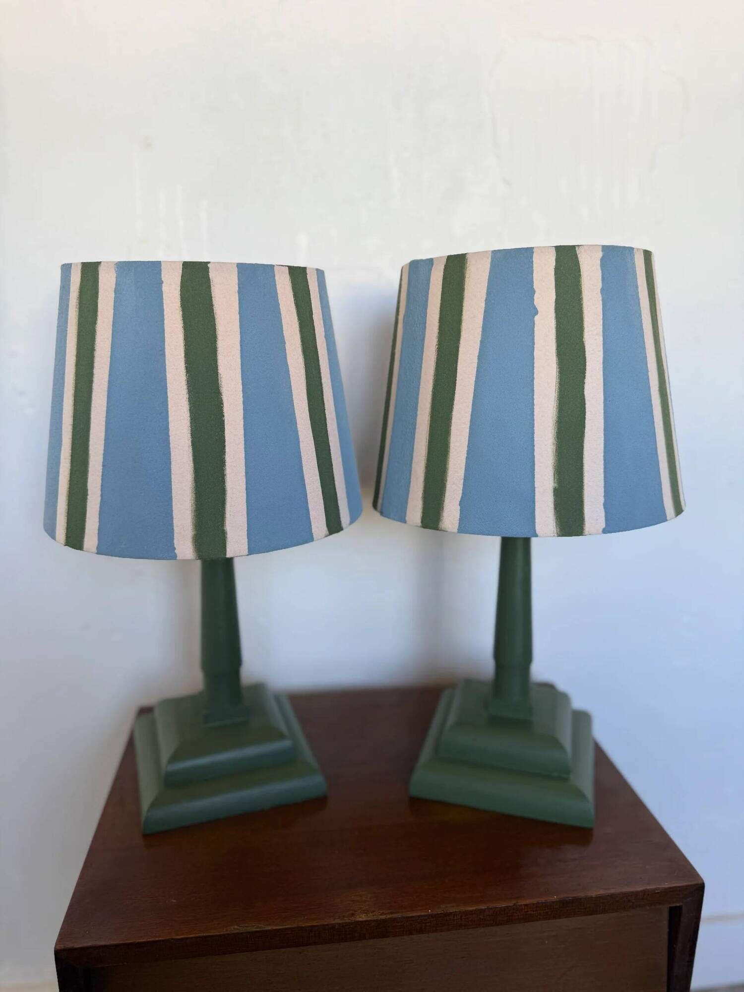 Pair of vintage wooden lamps with their striped beige, blue, and green shades.