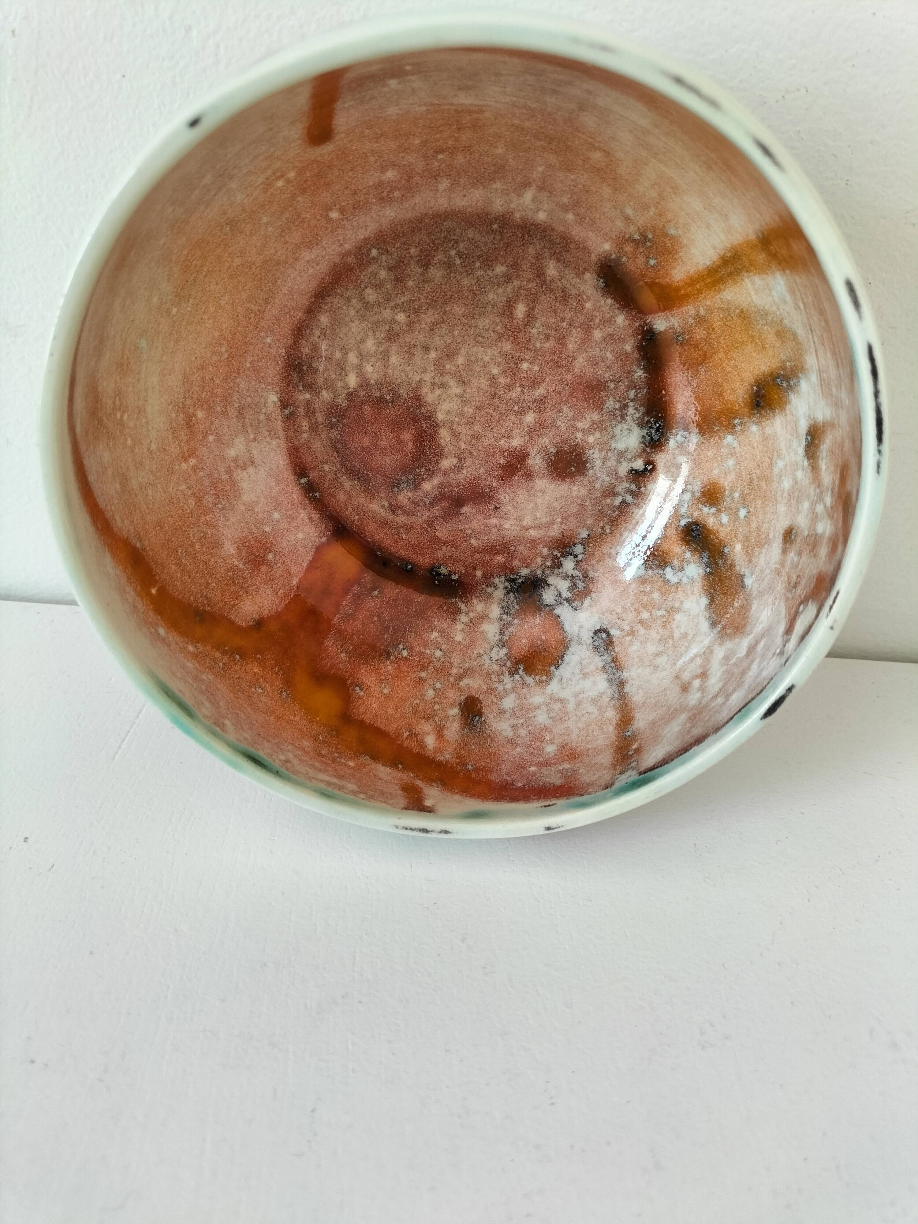 Red-orange glazed ceramic workshop bowl with floral decoration.