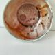 Red-orange glazed ceramic workshop bowl with floral decoration.