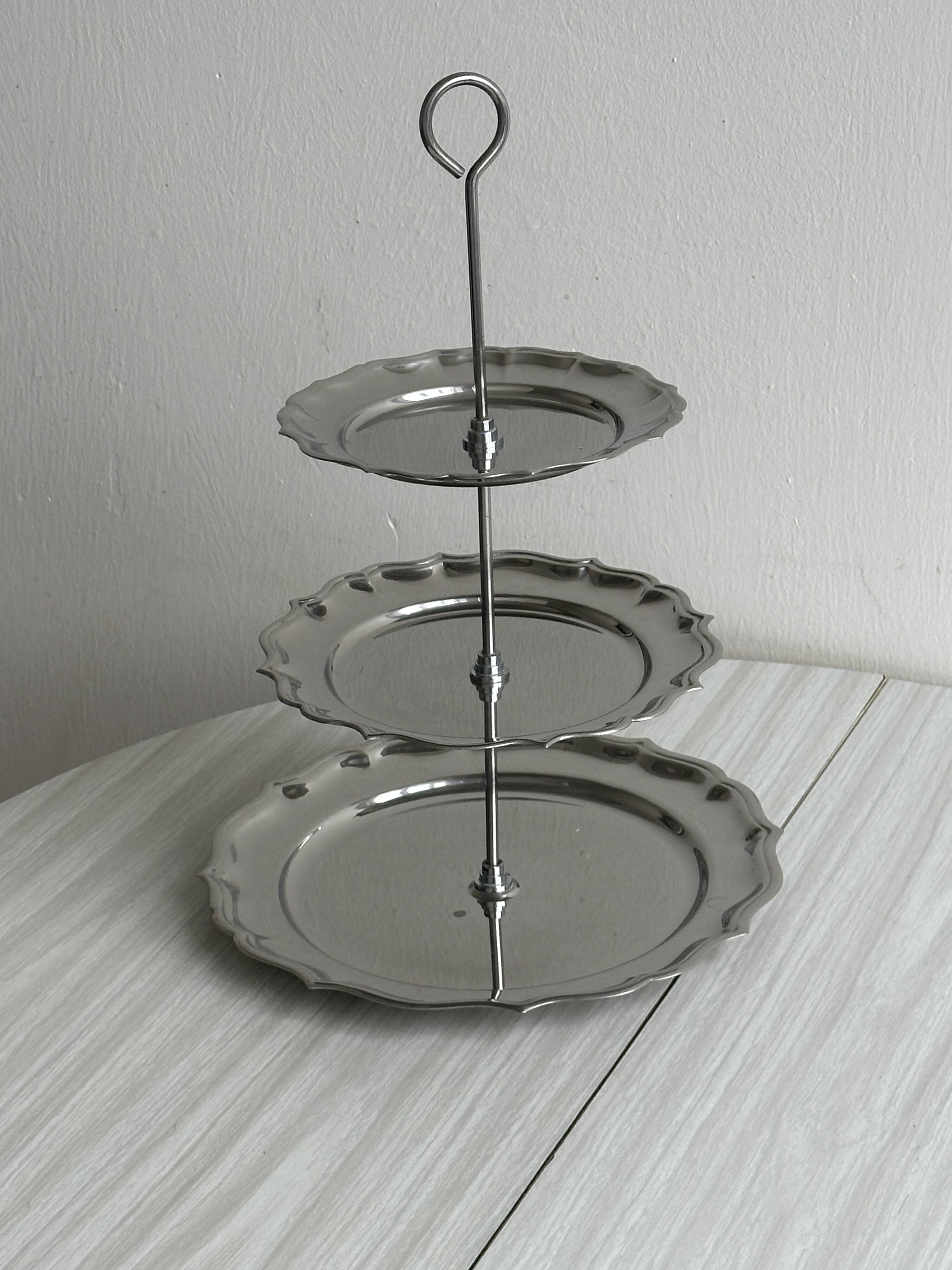 Three-tiered serving trolley in shiny stainless steel.