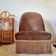Brown velvet crapaud armchair with fringes and sculpted legs.