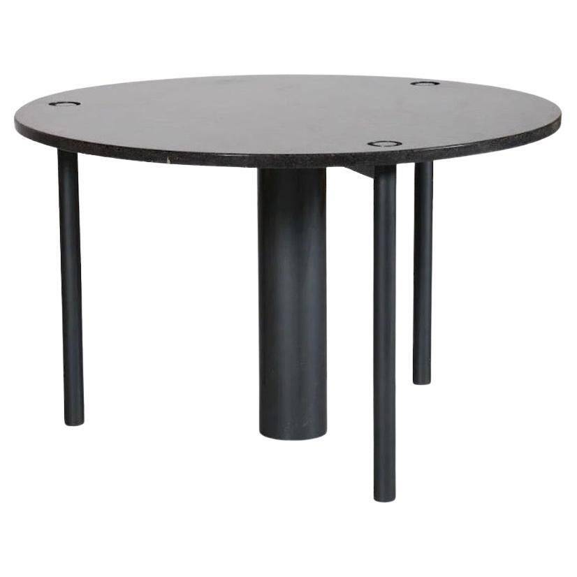Round dining table in black lacquered metal with a granite top.