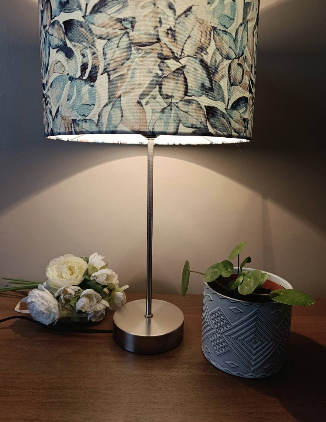 Table lamp with chrome stem, tropical plant shade.