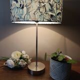 Table lamp with chrome stem, tropical plant shade.