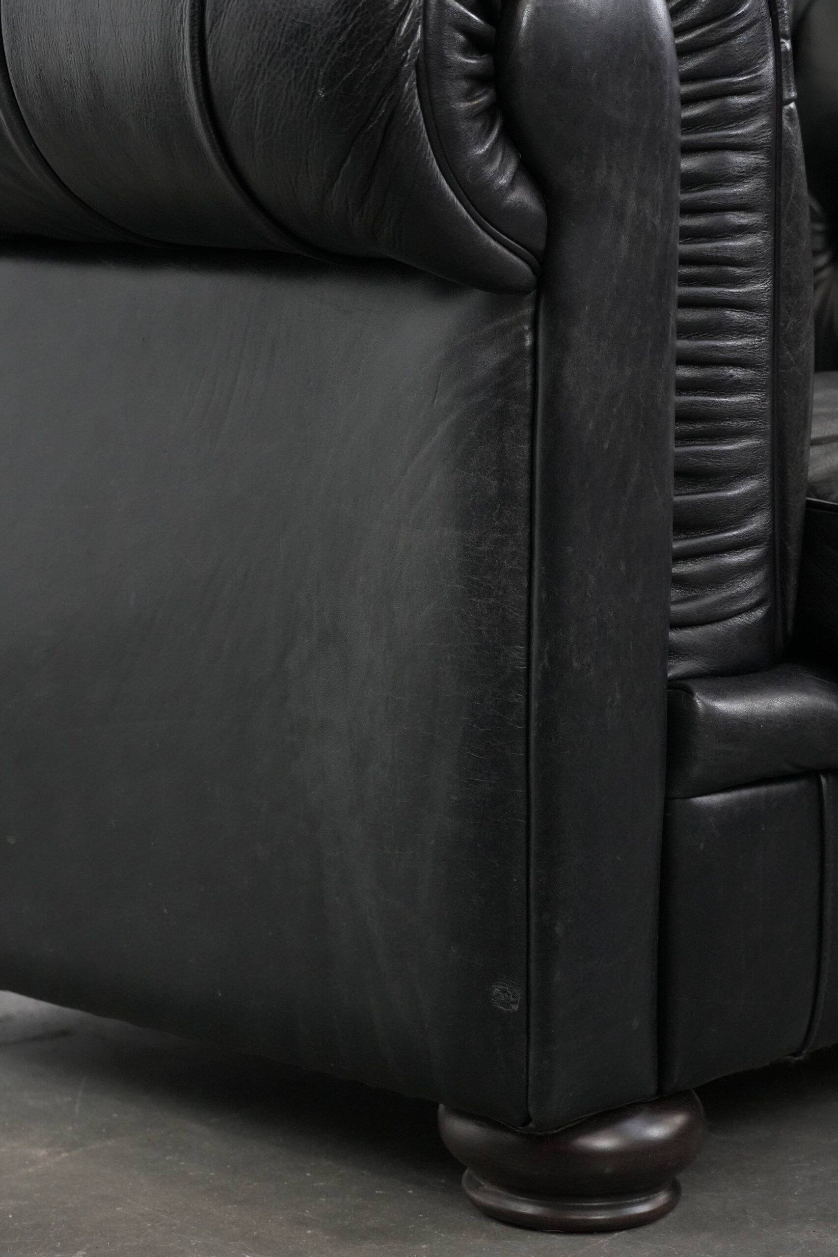 Comfortable black chesterfield armchair made of cowhide leather