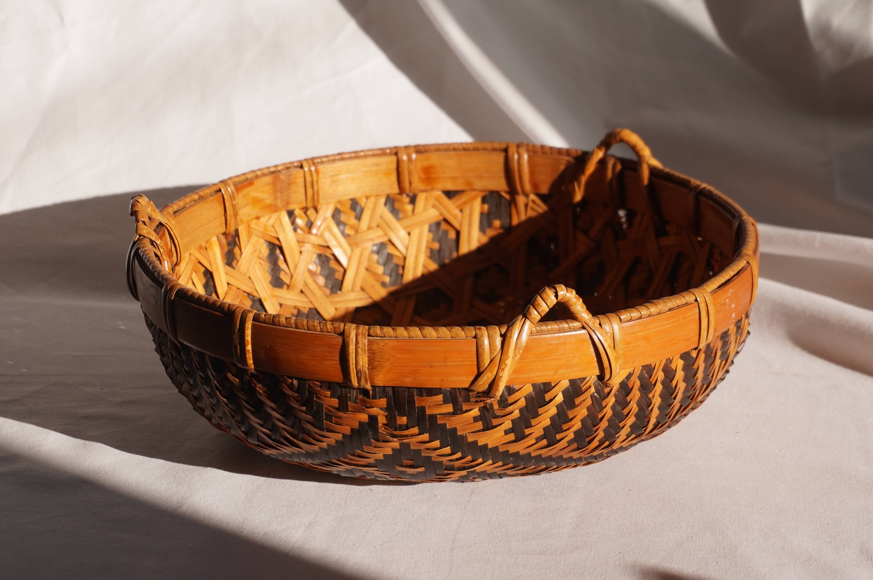 Woven patterned basket, made of straw and bamboo.