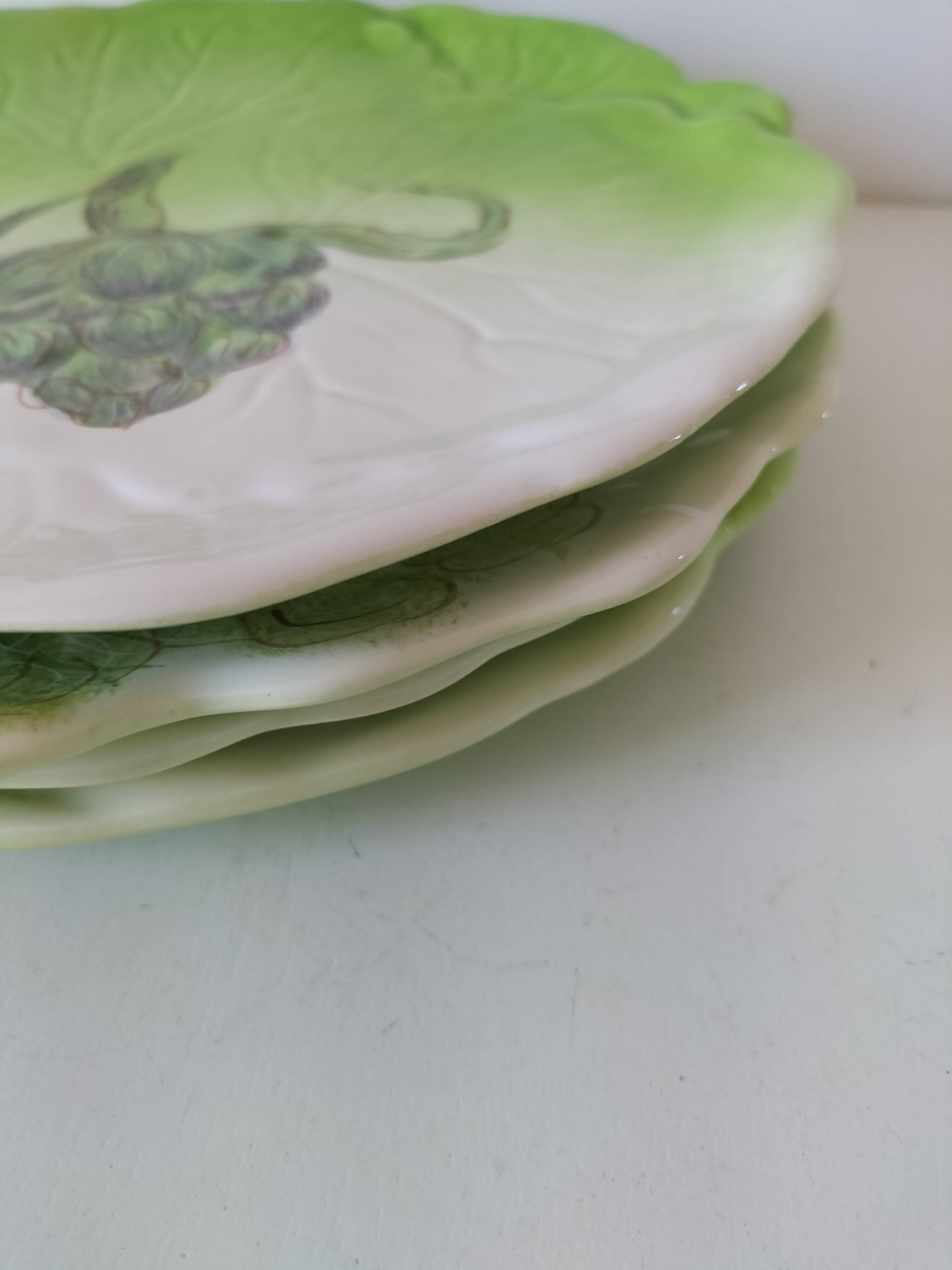 4 hand-decorated earthenware plates with vegetable and green leaf designs.