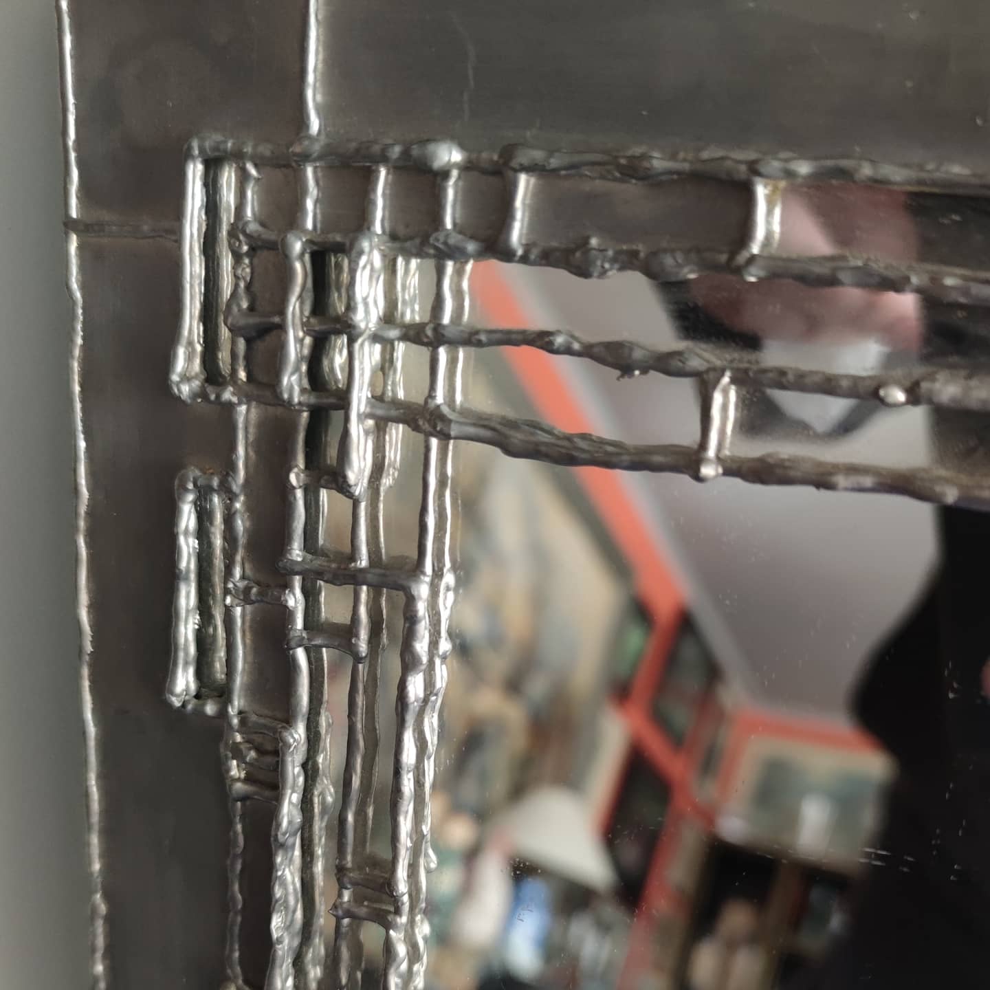 Pewter mirror on a brutalist-style wooden stand