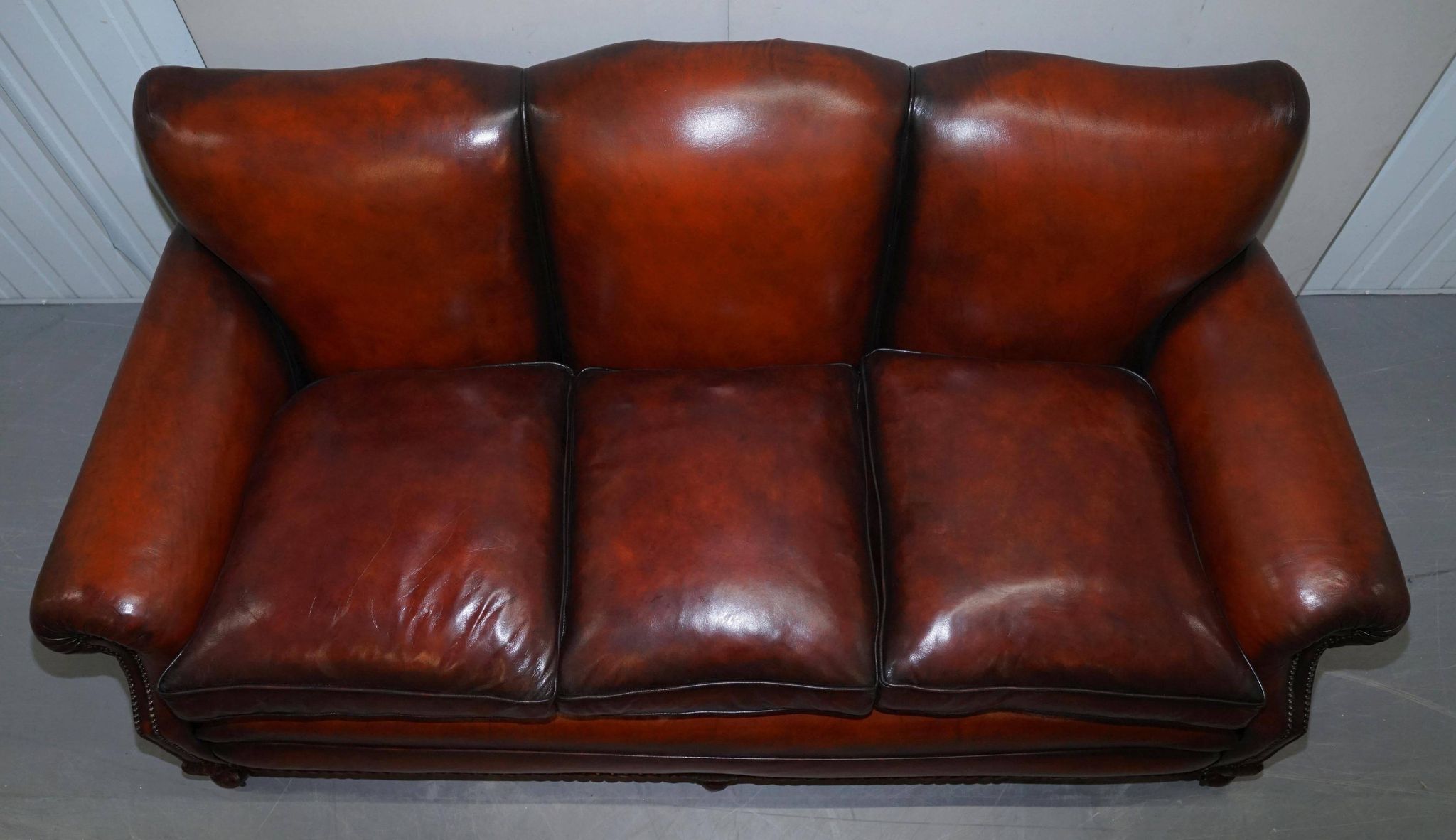Restored Victorian sofa in leather with claw feet and feather cushions.