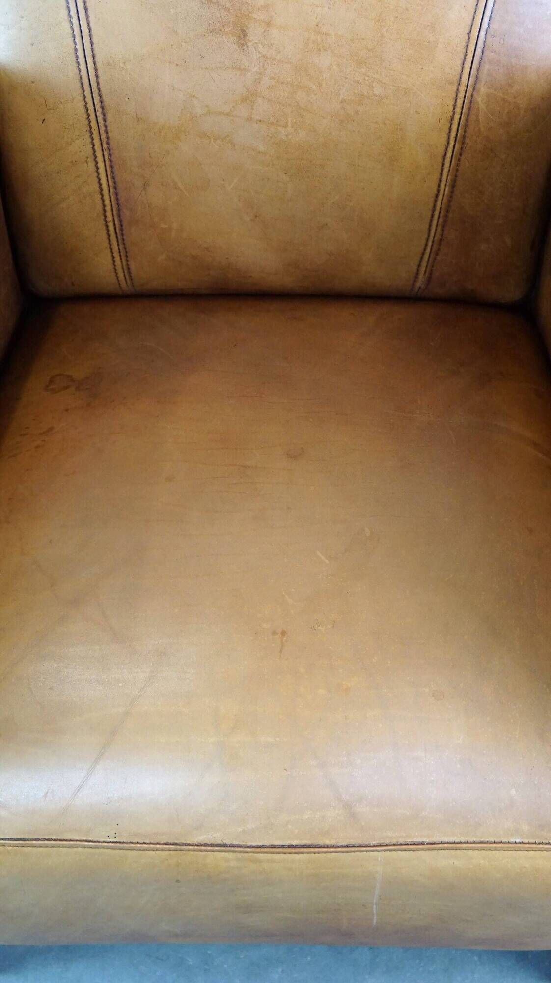 Luxurious cowhide Art Deco design armchair with wooden armrests and cognac-colored leather