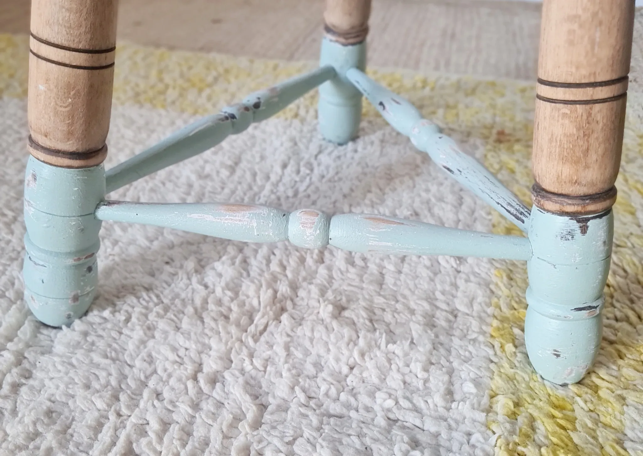 Antique tripod stool with blue striped seat.