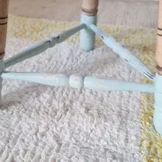 Antique tripod stool with blue striped seat.