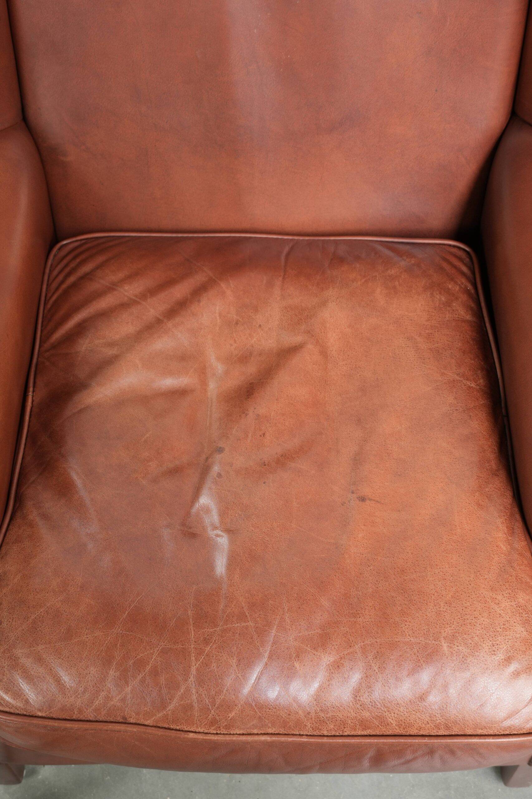 Cognac-coloured cow leather wingback armchair in English style