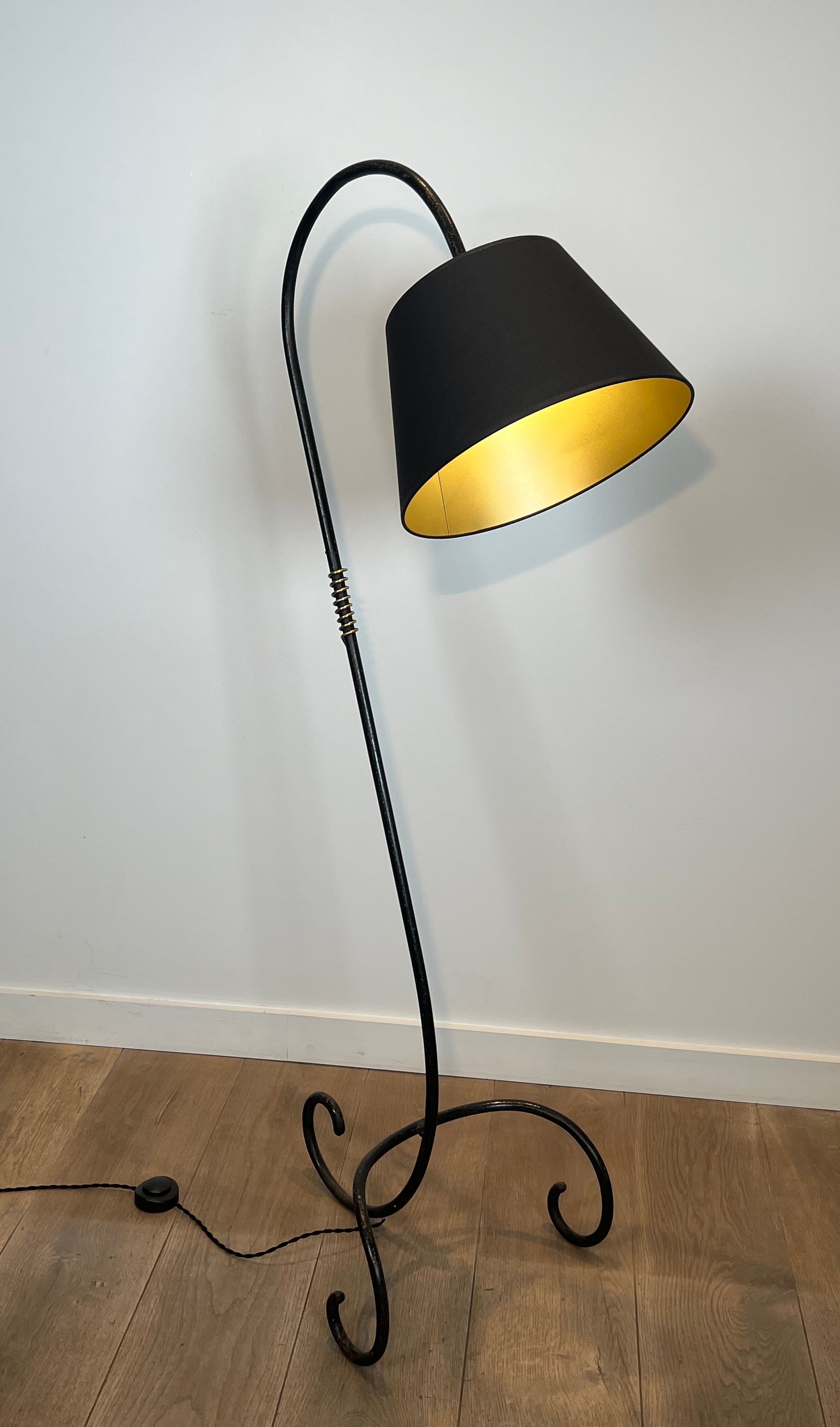 Design floor lamp in black lacquered metal and brass.