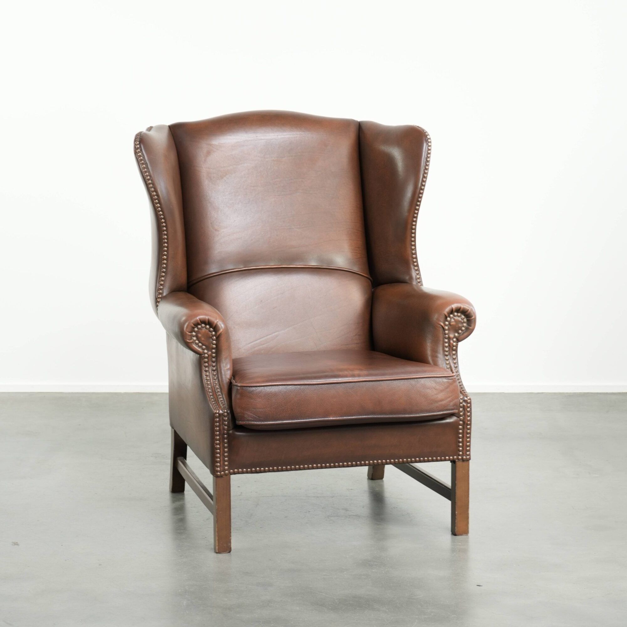 Cowhide wingback armchair in English style finished with decorative nails