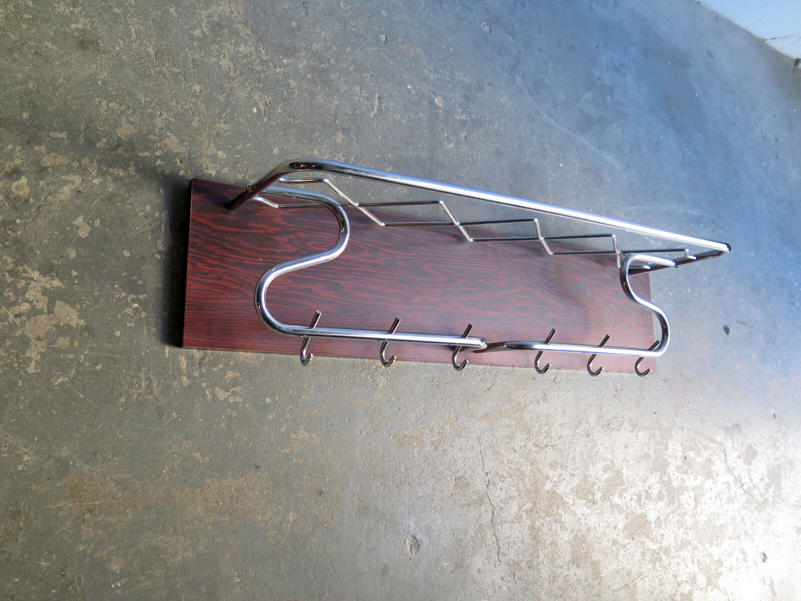 Chrome metal patere in a wooden support panel coat veneer.