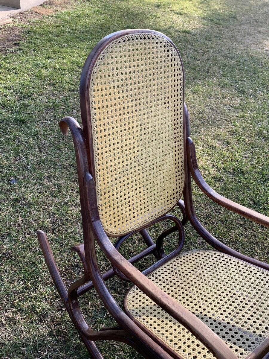 Thonet rocking chair in curved brown wood, period seat, 19th-century bentwood style.