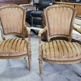 A pair of gilded wooden armchairs in the Louis XVI style.