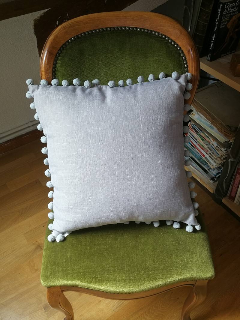 Gray cushion with pompoms