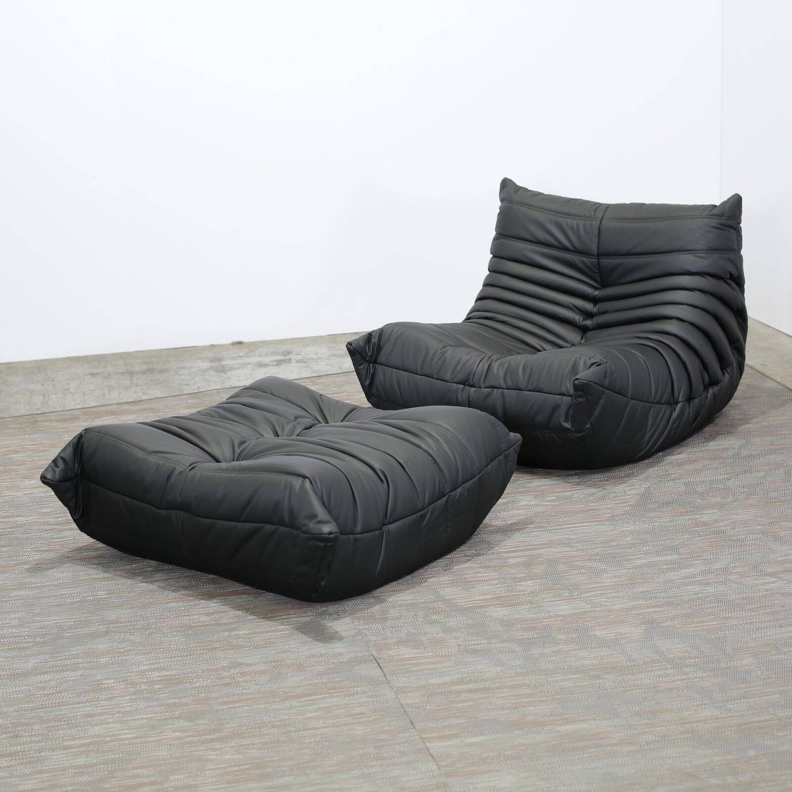Togo armchair and footrest in black leather by Ligne Roset, designed by Michel Ducaroy.