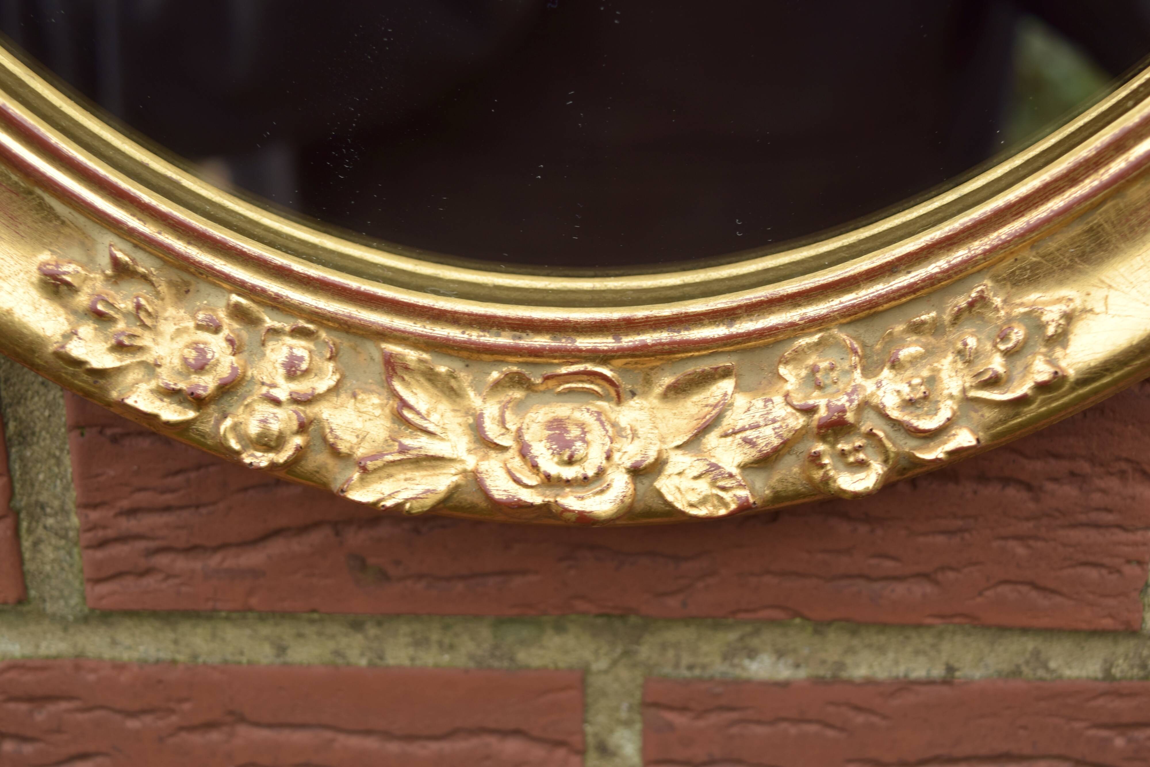 Old large oval wall mirror in golden resin