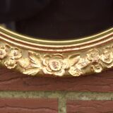 Old large oval wall mirror in golden resin