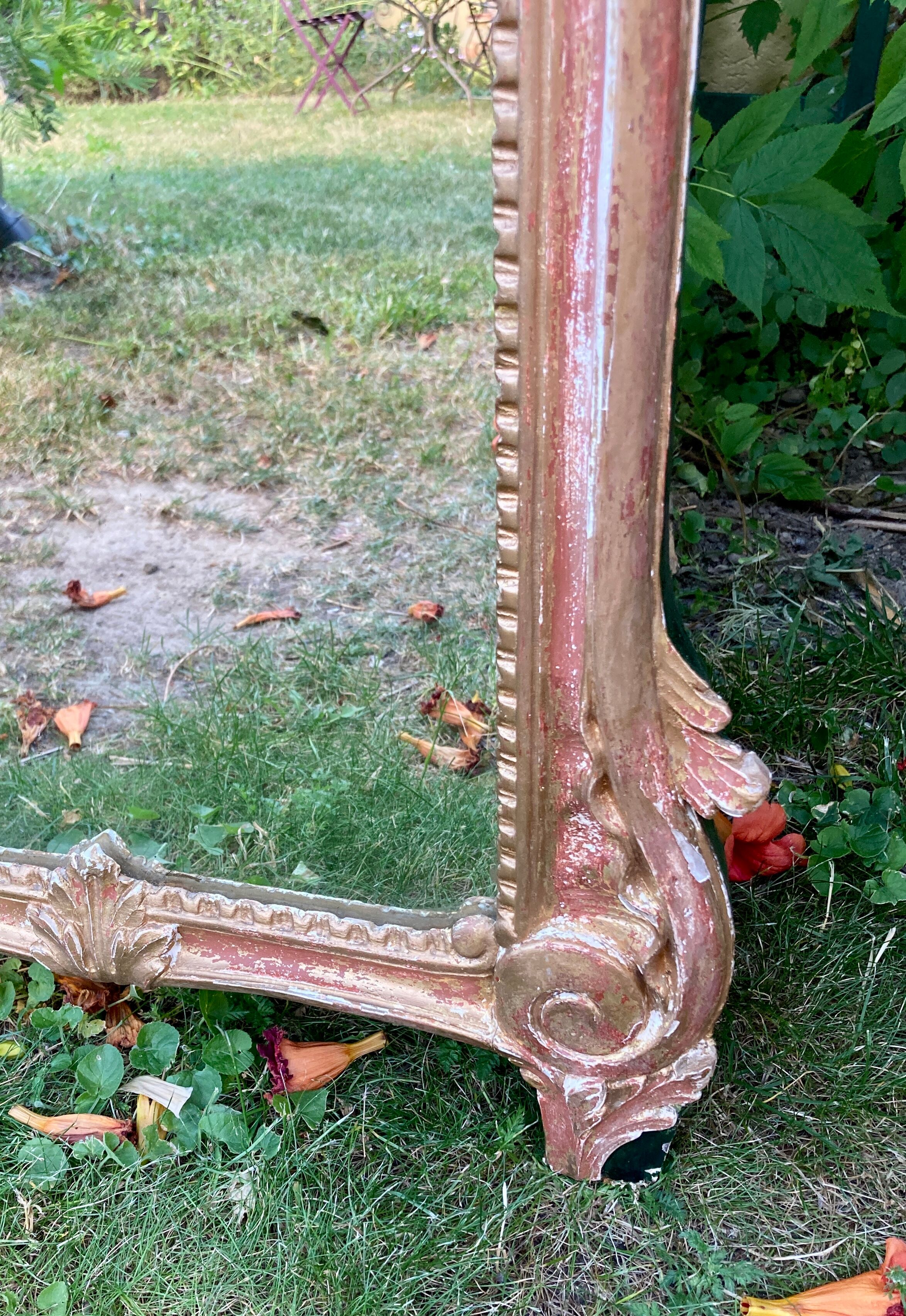 Mirror above a wooden and gilded stucco fireplace in the style of the 18th century.