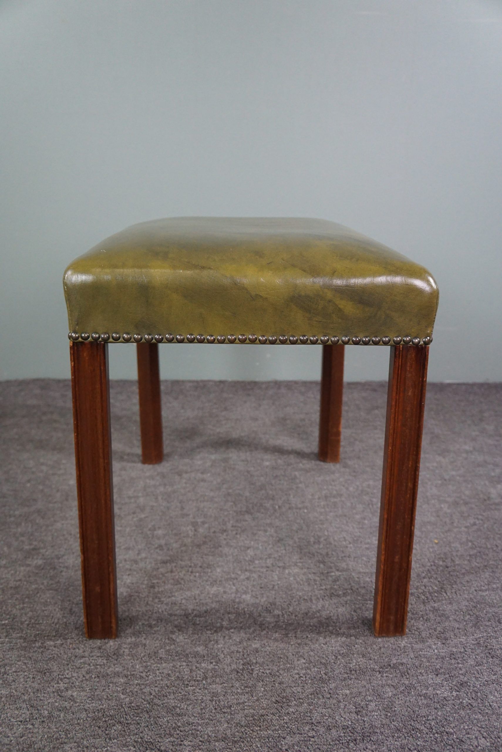 Elegant armchair and footrest in English green leather