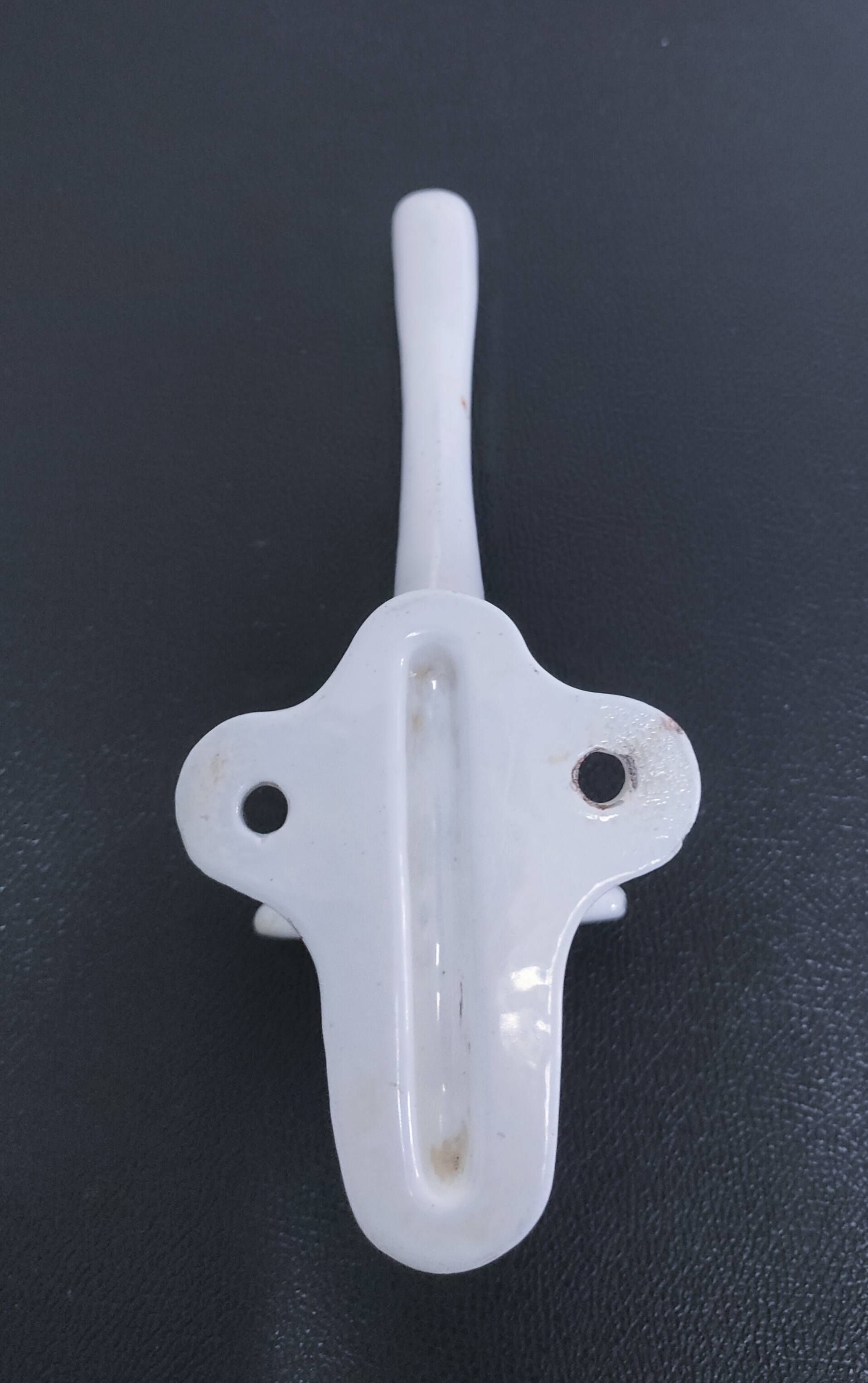 Three enameled cast iron coat hooks and vintage patina metal