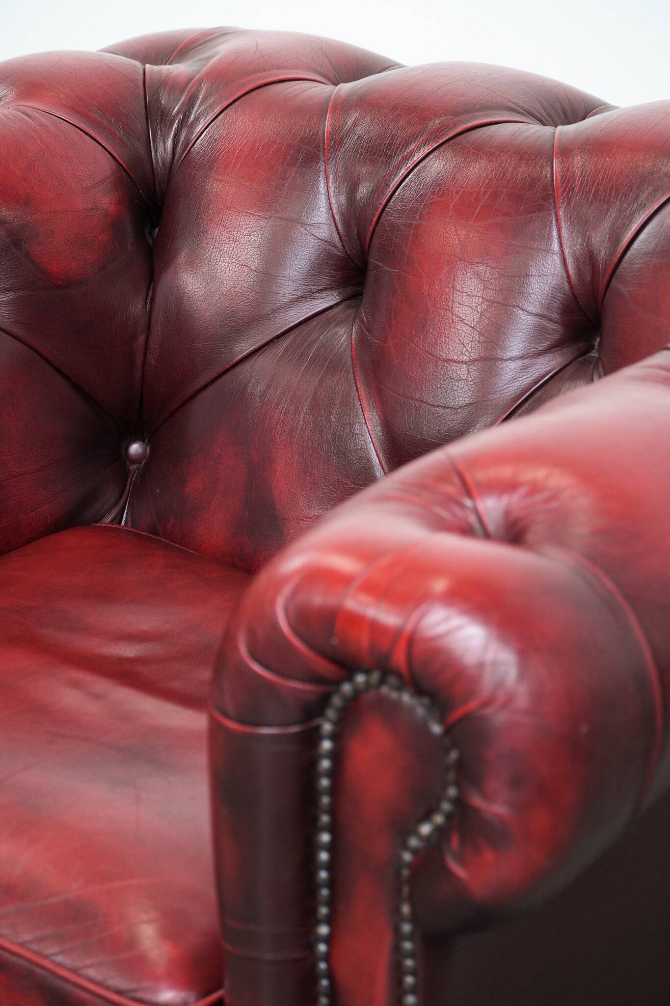 Red English cowhide Chesterfield armchair finished with decorative nails