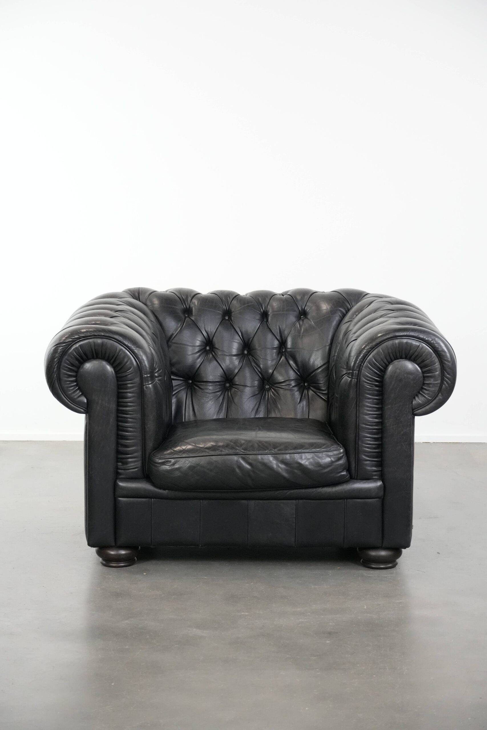 Ensemble composé d'un canapé chesterfield noir, d'un fauteuil et d'un pouf.