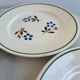 Set of 4 small flat plates with floral designs.