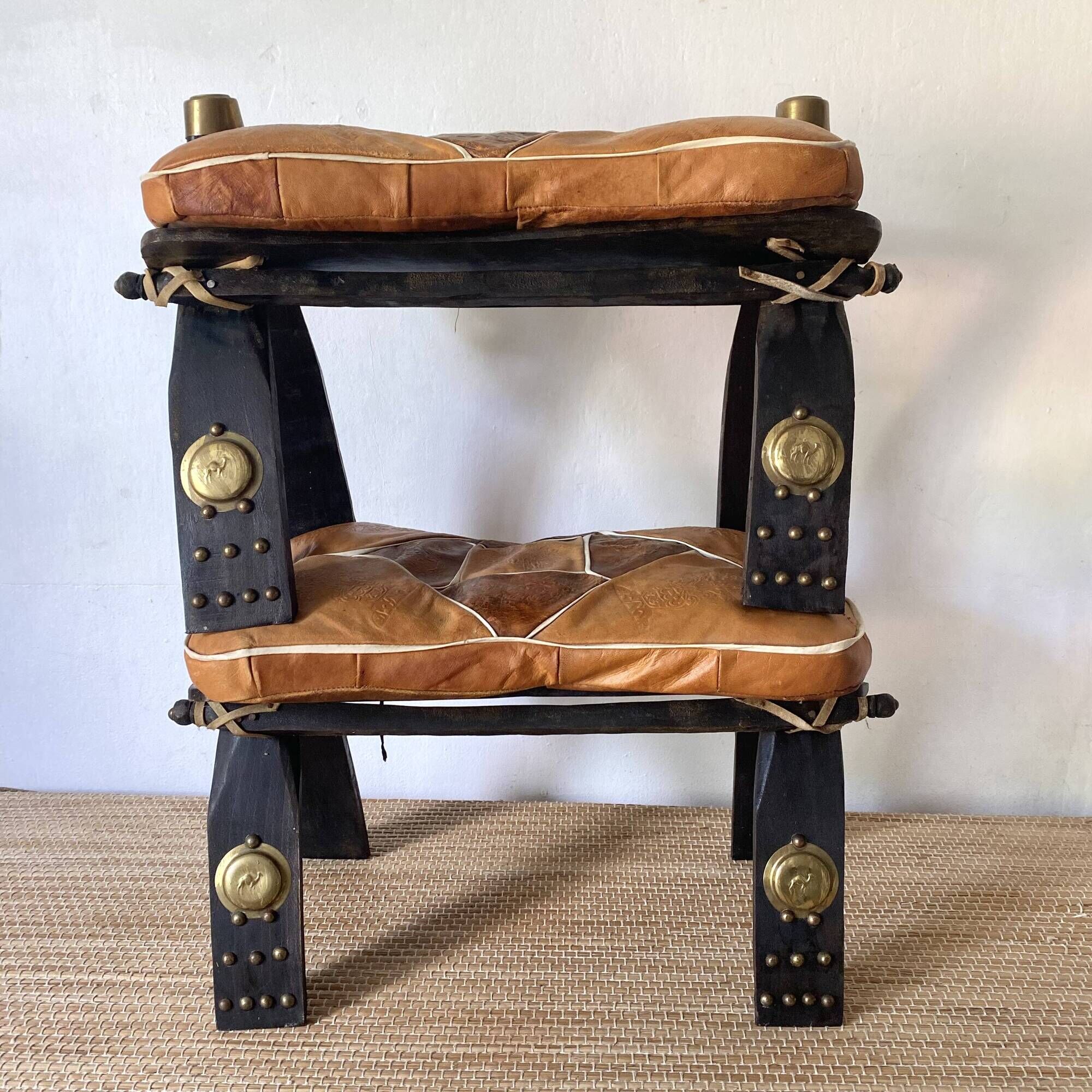 Pair of low Egyptian stools, camel saddles in wood, leather and brass