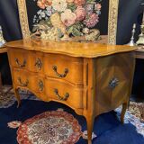 Large bow-fronted chest of drawers in blonde cherry with bronze ornamentation.