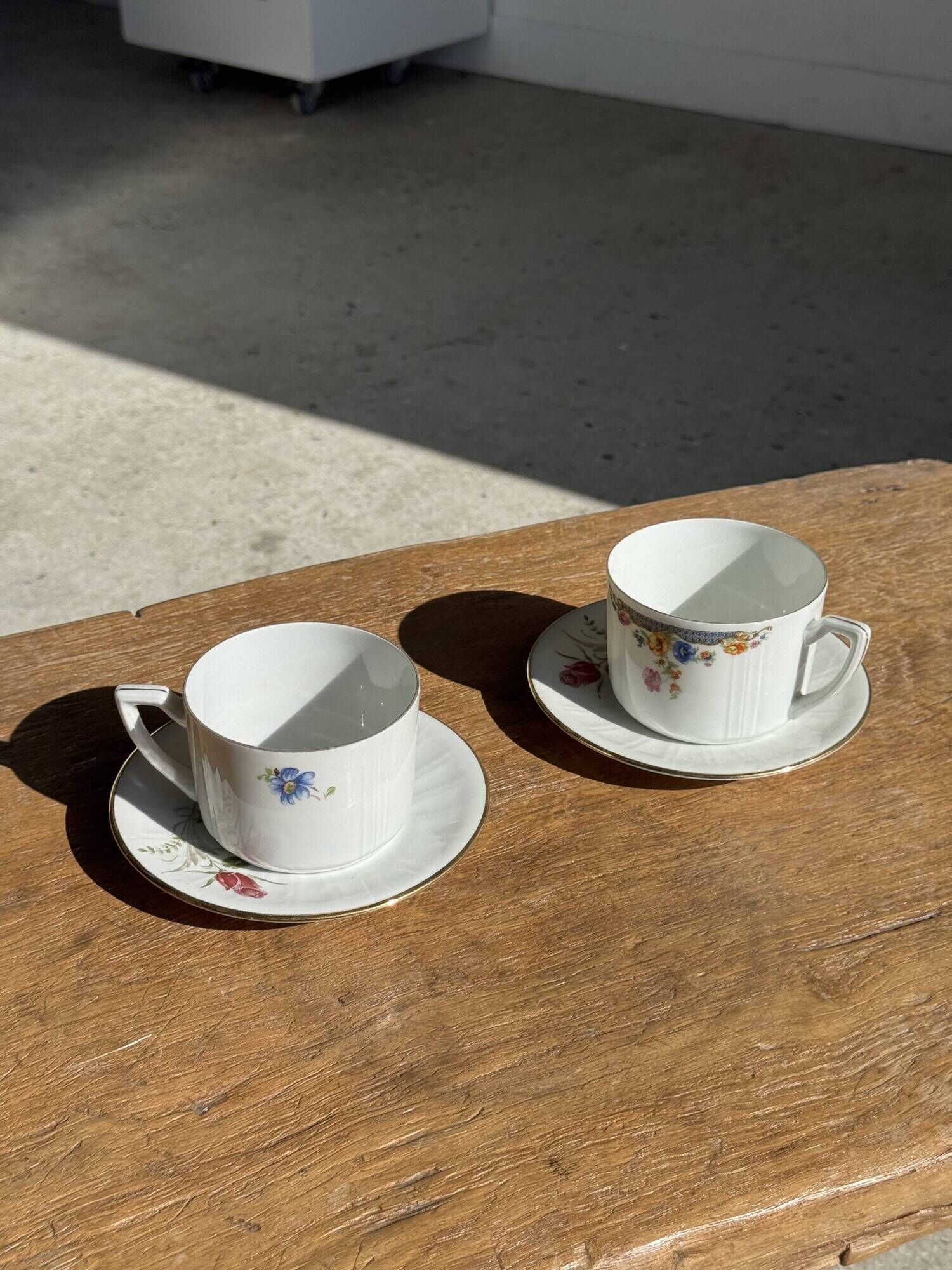 Pair of white porcelain cups from ADP France with a floral pattern and their s