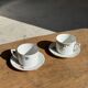 Pair of white porcelain cups from ADP France with a floral pattern and their s