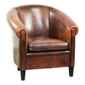 Fauteuil club en peau de mouton avec des couleurs chaudes et profondes et un passepoil noir.