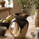 Stoneware jug with deep black drips on a sandy background.