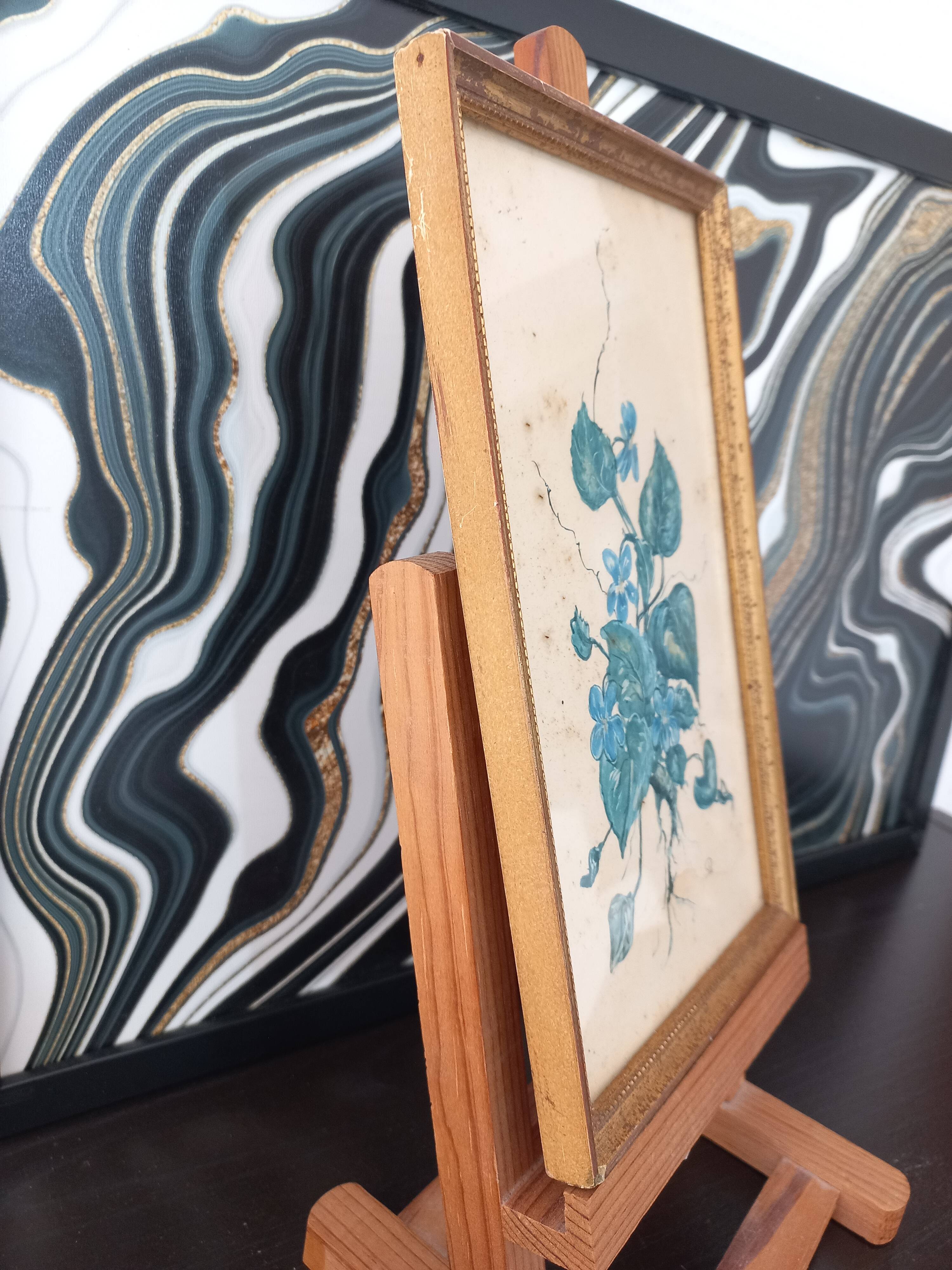 Decorative table with vintage blue flowers in a golden frame.