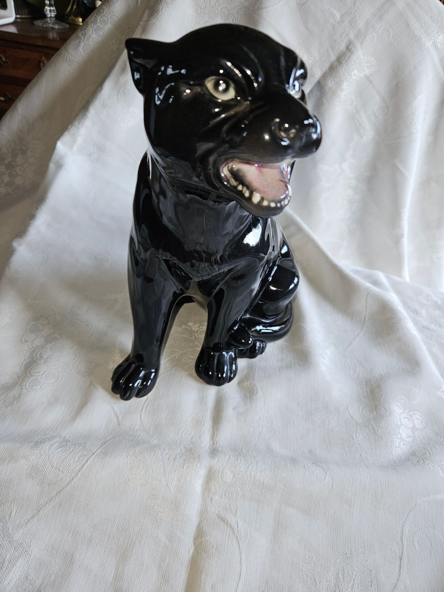 Statue of a roaring panther/leopard sitting in black glazed ceramic.