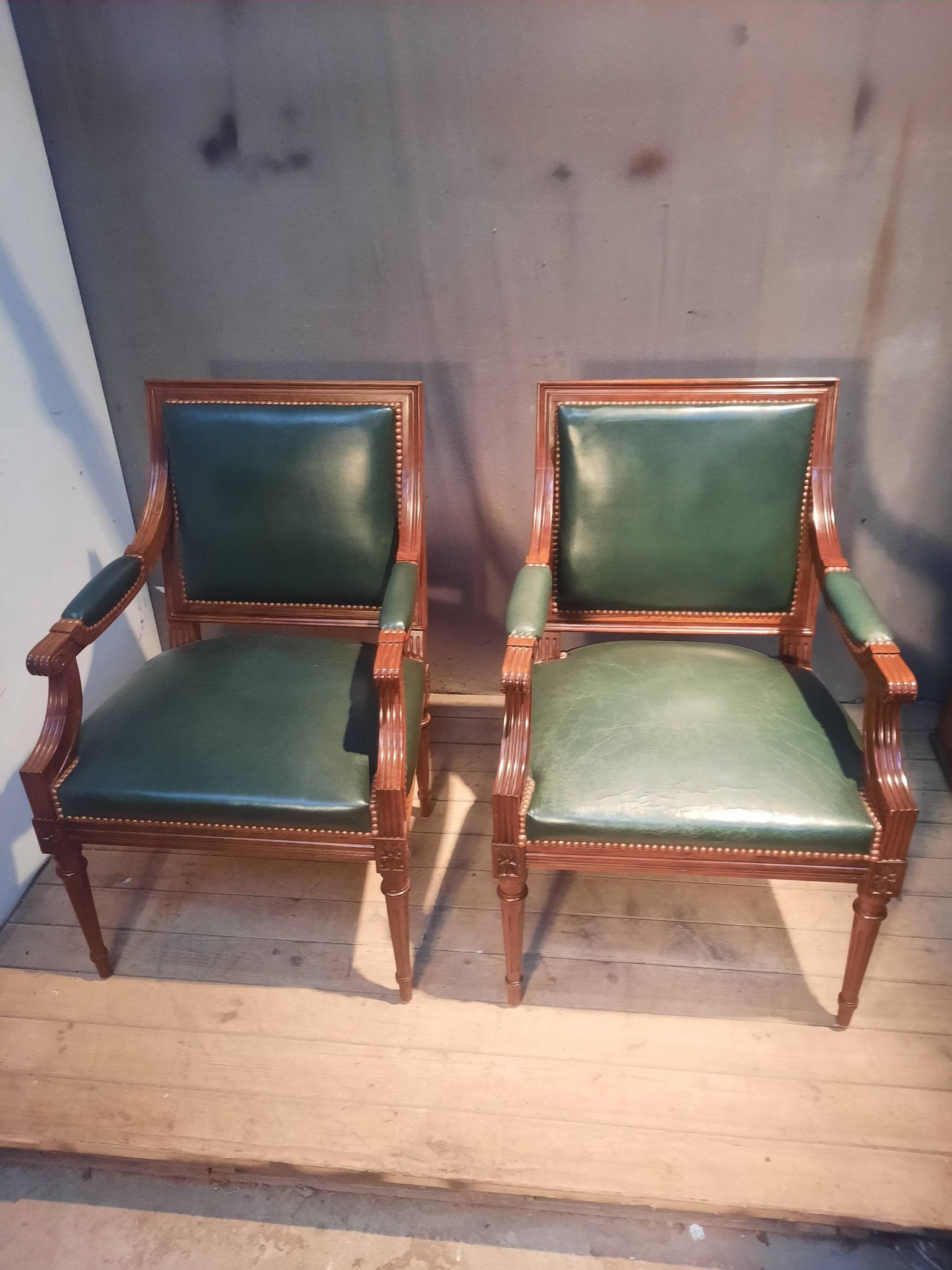 Pair of Louis XVI style armchairs upholstered in green leather.