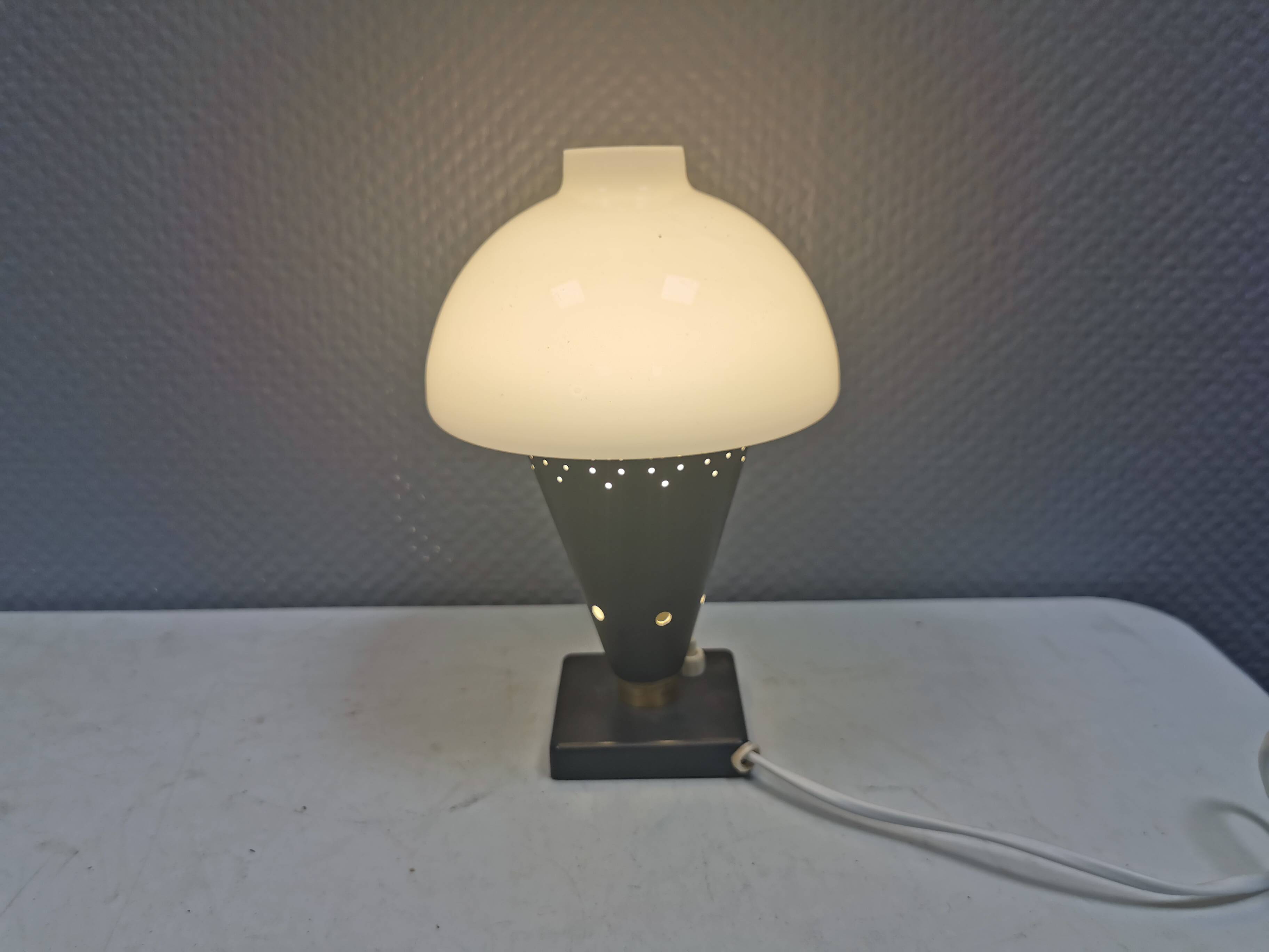 Small stylish table lamp with perforations and milky white opal glass shade