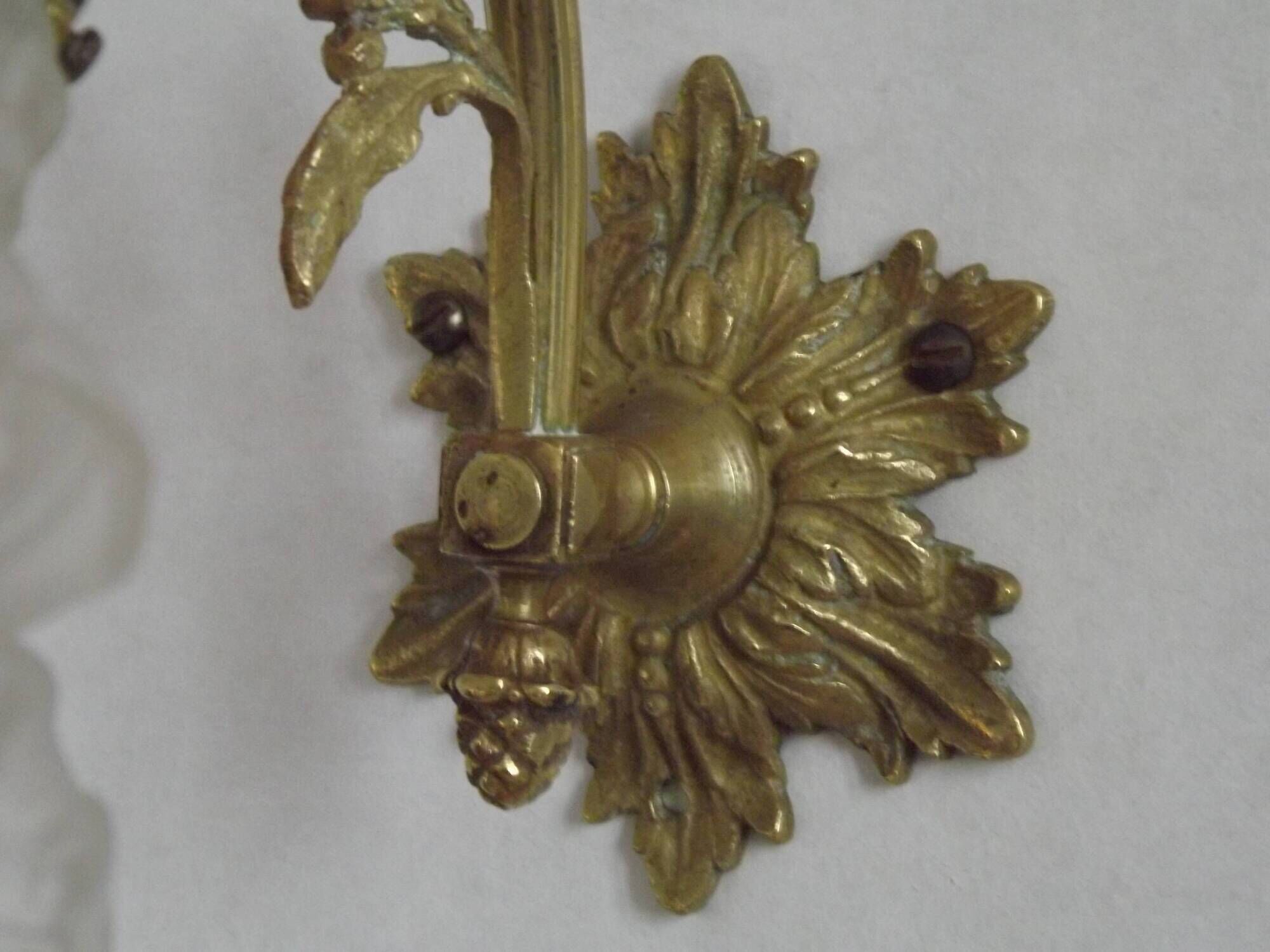 Simple wall sconce in French Art Nouveau bronze with a white glass shade featuring patterns.