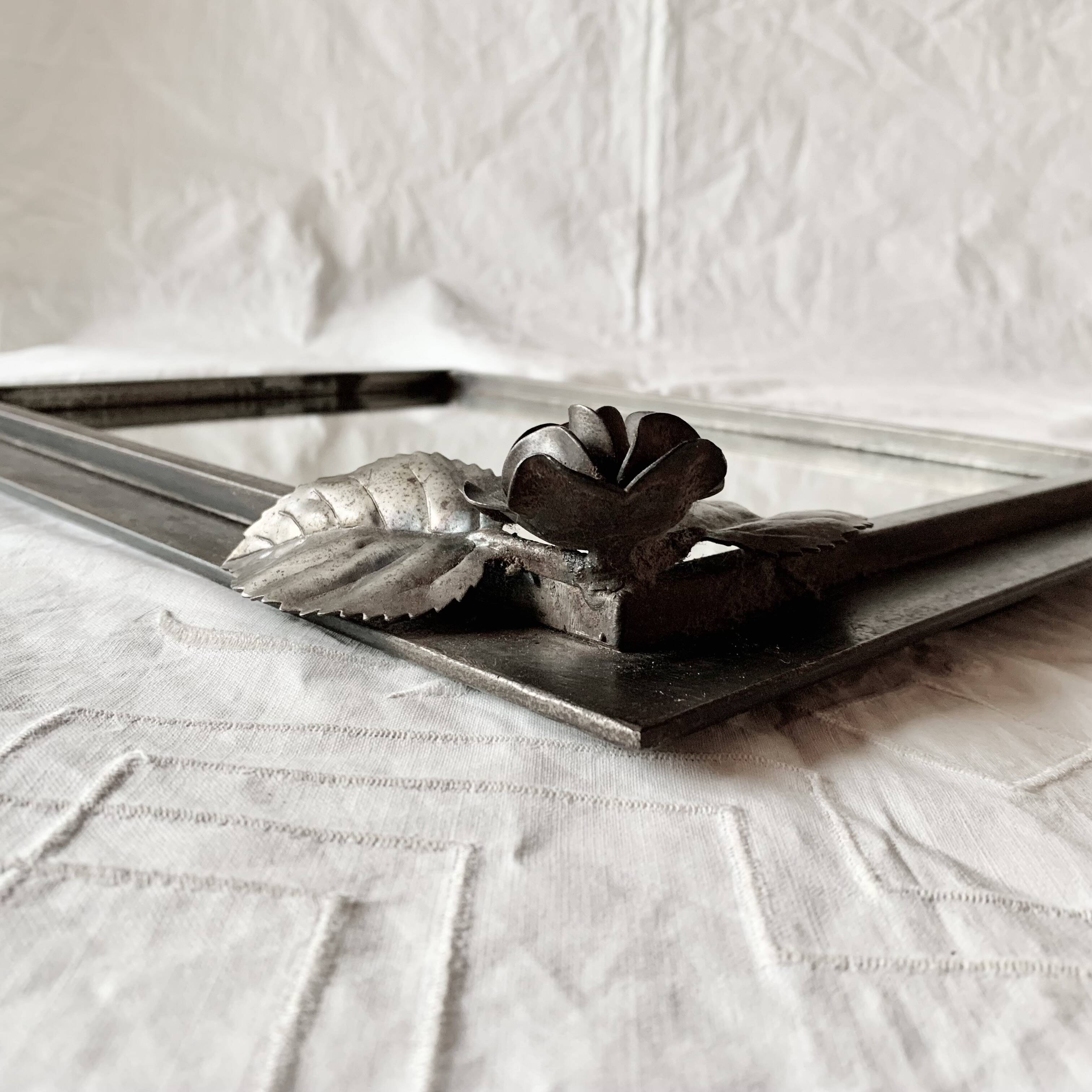 Vintage wall mirror in varnished steel decorated with a rose in relief