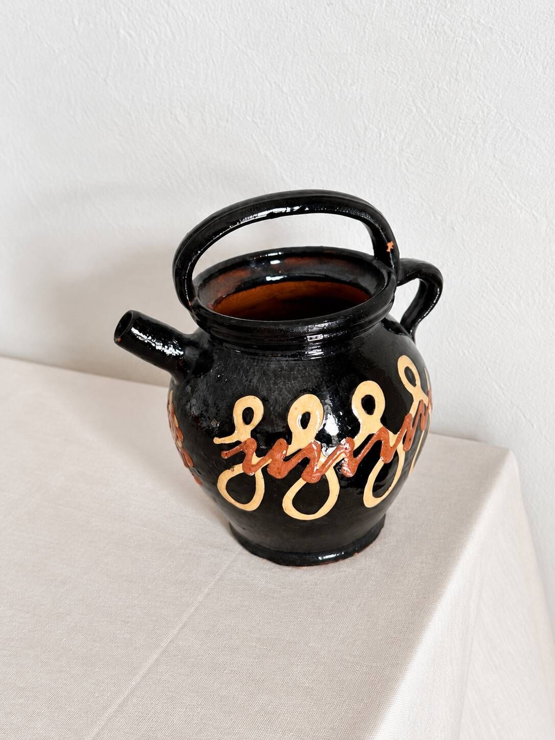 Old vase in glossy black ceramic, vintage exterior decoration.
